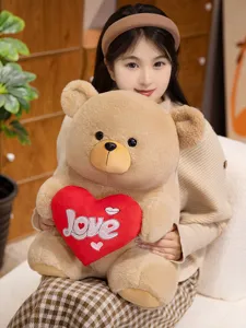 Cute brown teddy bear plush toy holding a red heart pillow with Love embroidery detail.