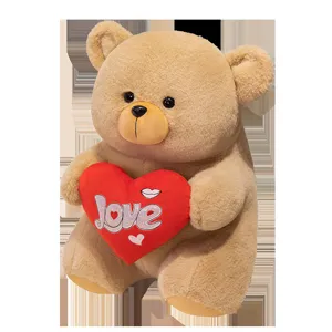 Detail view of a cute brown teddy bear plush toy holding a red heart with Love print.