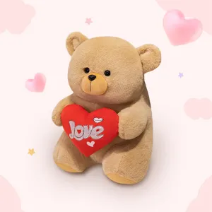 Cute brown teddy bear plush toy holding a red heart pillow, perfect romantic gift for holidays.