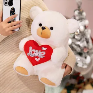 Cute white plush teddy bear holding red heart pillow with love embroidery, soft festival gift toy.