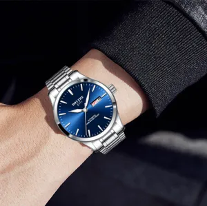 Detalle de reloj mecánico con esfera azul, correa de acero y visualización de fecha.