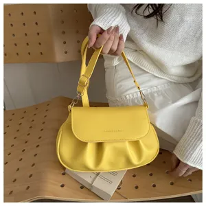 Detail view of the yellow gathered saddle bag, showing pleats, flap closure and texture.