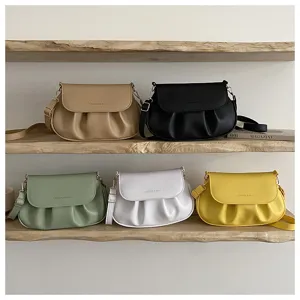 Detailed view of stylish pleated saddle bags in various colors on wooden display shelves.