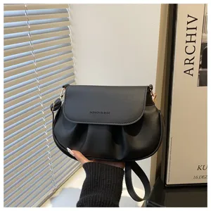 Elegant black ruched saddle bag with flap and metal buckle detail, stylish crossbody bag.