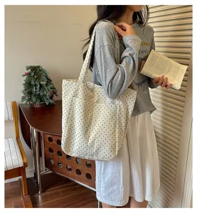 Detailed view of polka dot canvas tote bag in daily scene with front pocket and shoulder strap.