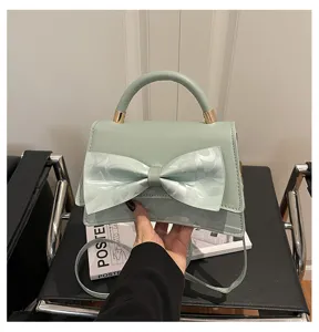 Close-up view of elegant mint green handbag bow detail, stylish crossbody bag hardware accent.