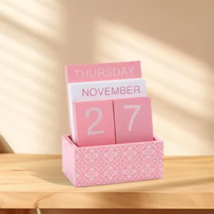 Wooden desk calendar detail showcasing pink and white blocks with elegant pattern base.