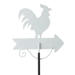 Close-up of white metal rooster garden stake and arrow silhouette detail for outdoor decor.
