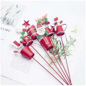 Close-up detail of Christmas metal plant stakes featuring mini watering cans and festive holiday figures.