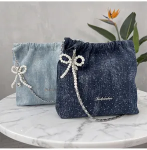 Τσάντα πουγκί denim ώμου με φιόγκος από μαργαριτάρια και μεταλλική αλυσίδα, λεπτομέρεια.