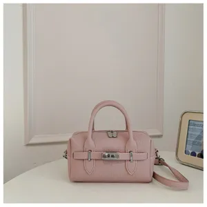 Detalle de bolso de hombro de cuero granulado rosa con correa de cierre metálica y asas dobles.