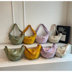 Detail view of casual nylon dumpling shoulder bags in multiple colors arranged neatly.