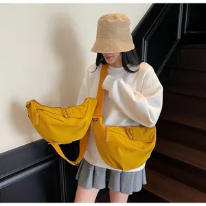 Detailed view of casual yellow nylon dumpling shoulder bag, wide strap and chic zipper design.