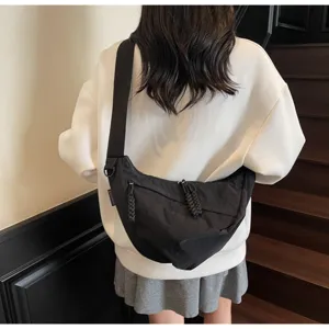 Detailed view of the stylish black nylon crossbody dumpling bag worn by model on indoor stairs.