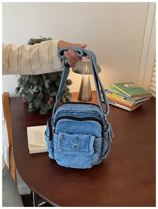 Vue détaillée du sac bandoulière en denim vintage avec poches multiples et bandoulière.