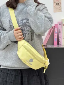 Close-up detail of the yellow canvas crossbody bag featuring cute embroidery and strap design.