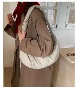 Vista detallada de un bolso de hombro beige suave y elegante llevado por la modelo.
