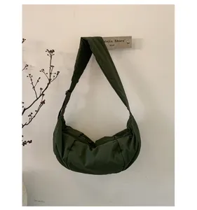 Bolso cruzado de nailon verde oscuro en media luna, detalle de diseño casual diario.