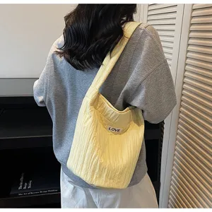Yellow quilted shoulder bag worn by model, casual soft crossbody bag with love label.