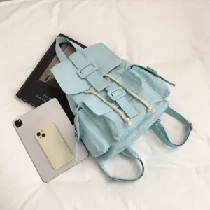 Mochila casual azul claro con cierre de cordón y hebilla, ideal para viajes y uso diario.