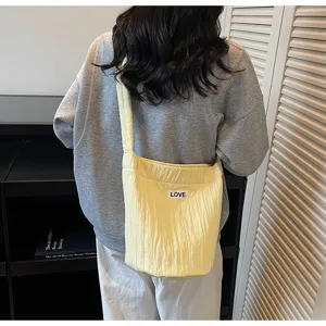 Detailed view of a stylish casual yellow shoulder bag worn on back, soft wrinkled fabric.
