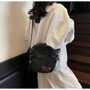 Gros plan sur le sac bandoulière rond en denim stylé avec broderie de teckel mignonne.