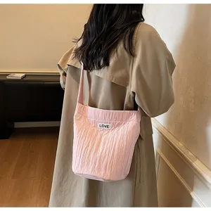 Detailed view of the pink casual shoulder bag with crinkled texture and love label in daily scene.