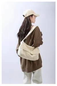 Close-up of casual canvas messenger bag worn on shoulder, durable fabric design for daily use.