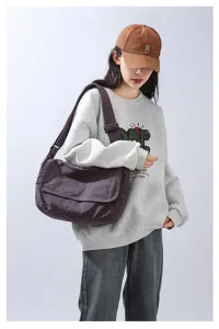 Detail view of the casual cotton canvas messenger bag worn by model, showing wide strap and flap.