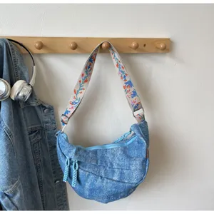 Casual denim crossbody bag with embroidered strap, trendy crescent shoulder bag for street wear.