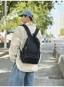 Outdoor street style detail shot showing a black denim backpack worn by a model clearly.