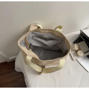 Detailed view of the beige canvas tote bag interior, showing large capacity and zipper pocket.