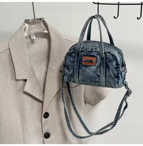 Denim handbag detail view featuring retro washed fabric, dual top handles and strap.
