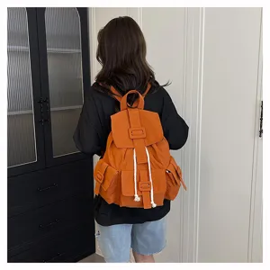 Vista posterior detallada de una mochila de lona naranja con bolsillos prácticos.