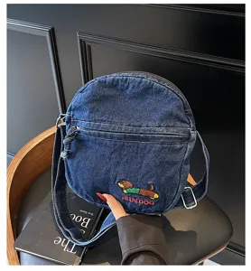 Vue detaillee du joli sac bandouliere en denim brode avec une poche zippee pratique.