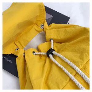 Detalle de mochila con cordón de nailon amarillo con ojales metálicos y cordón blanco.