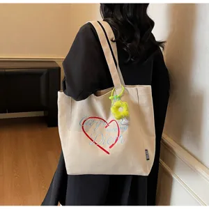 Λεπτομερης οψη της casual τσαντας tote απο καμβα με κομψο σχεδιο κεντηματος και μπρελοκ λουλουδιου.