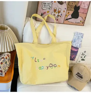 Detalle de bolso tote de nylon amarillo, bolso de hombro casual grande con bonito bordado.