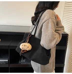 Casual black suede tote bag, large capacity shoulder bag with plush pendant, autumn winter commuting.