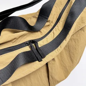 Close-up view of the durable khaki crossbody bag featuring thick black straps and double zippers.
