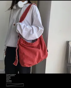 Detailansicht der stylischen roten Canvas-Umhängetasche mit Fransen, lässig vom Model getragen.