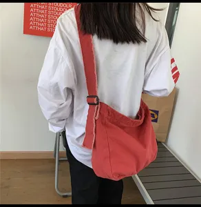 Detailansicht der roten Canvas-Umhängetasche mit verwaschenem Look und modischem Design.