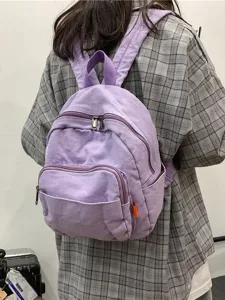 Purple canvas backpack for women, casual small daypack with zipper pockets and top handle.