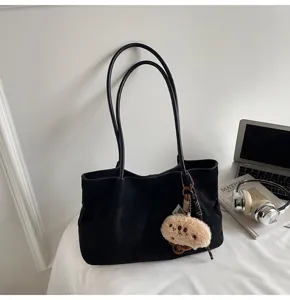 Classic black minimalist tote bag detail shot, large capacity shoulder bag with cute plush pendant.