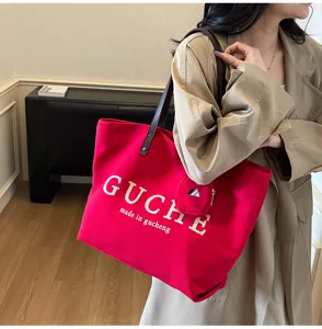Detail view of large red canvas tote bag with shoulder straps and mini pouch for daily commuting.