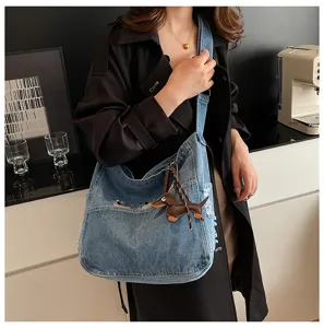 Detailed view of the stylish denim shoulder bag with a cute dachshund charm and embroidery.