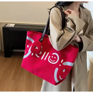 Detail view of the red canvas tote bag with hello print, shoulder strap and mini pouch.