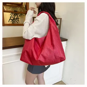Detail view of the large capacity red shoulder bag in an indoor lifestyle setting.