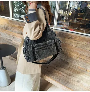 Detailed view of a retro washed denim shoulder bag featuring multiple zippered pockets for daily use.
