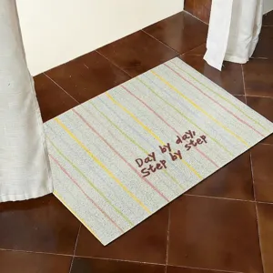 Close-up detail of a striped doormat featuring motivational text for home entryways.